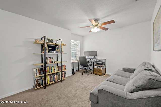 home office featuring light carpet, ceiling fan, baseboards, and a textured ceiling