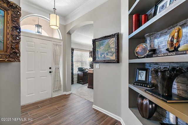 entryway with ornamental molding and a textured ceiling