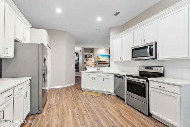 kitchen featuring tasteful backsplash, sink, white cabinets, stainless steel appliances, and light hardwood / wood-style flooring