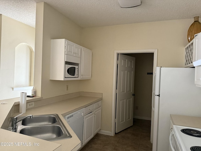 kitchen with white cabinetry, sink, dark tile patterned floors, white appliances, and a textured ceiling