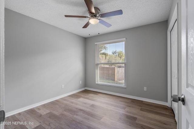 spare room featuring ceiling fan, light hardwood / wood-style floors, and a textured ceiling