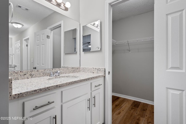 bathroom with vanity, wood-type flooring, and a textured ceiling