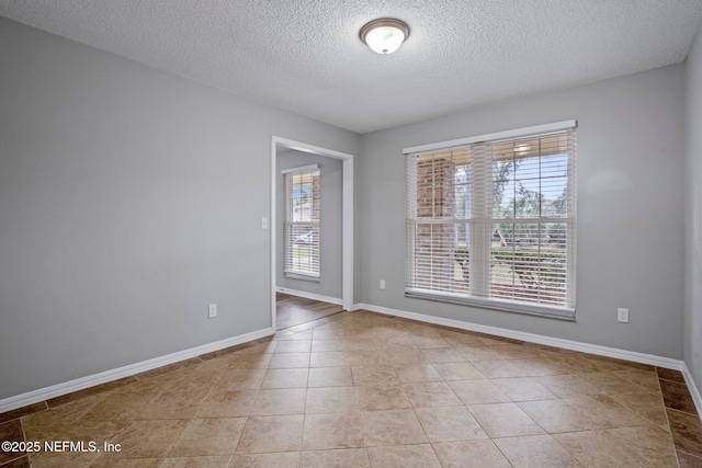 spare room featuring light tile patterned floors and a textured ceiling