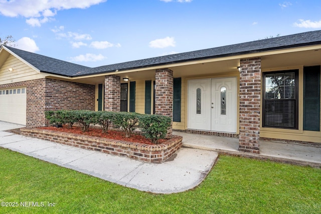 view of exterior entry with a yard, a garage, and a porch