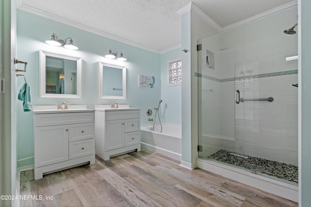 bathroom featuring crown molding, hardwood / wood-style floors, vanity, a textured ceiling, and separate shower and tub