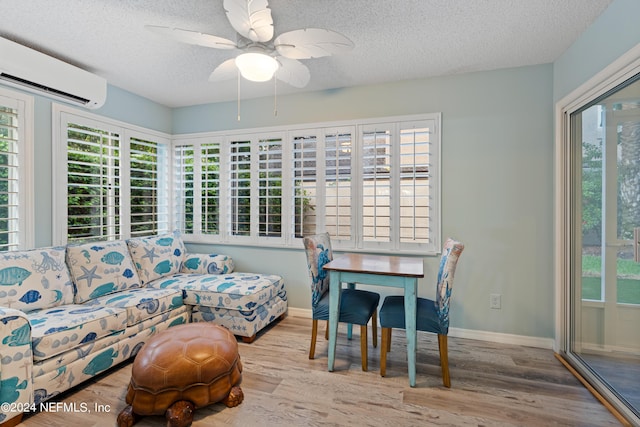 living room featuring hardwood / wood-style floors, an AC wall unit, a textured ceiling, and ceiling fan