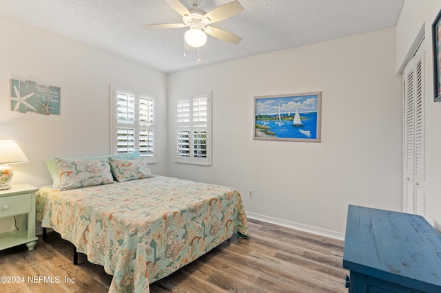 bedroom featuring ceiling fan, a closet, wood-type flooring, and a textured ceiling