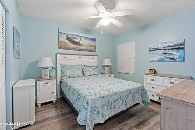 bedroom with dark wood-type flooring, ceiling fan, and a textured ceiling