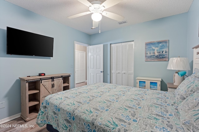 bedroom featuring ceiling fan, a textured ceiling, light wood-type flooring, and a closet