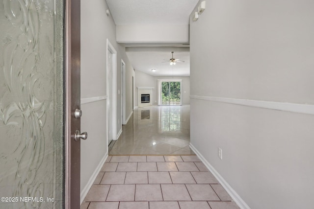 corridor featuring a textured ceiling and light tile patterned floors