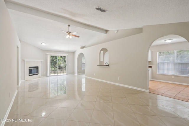 unfurnished living room with vaulted ceiling with beams, light tile patterned floors, a textured ceiling, and ceiling fan