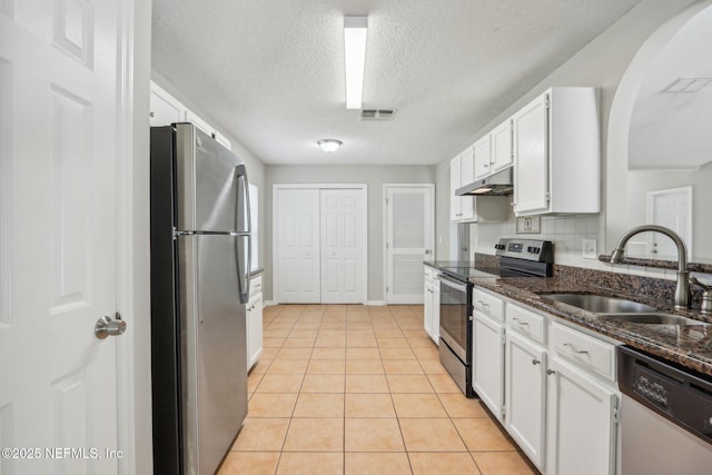 kitchen with dark stone countertops, appliances with stainless steel finishes, sink, and white cabinets