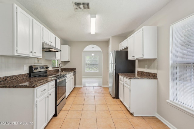 kitchen featuring dark stone countertops, backsplash, white cabinets, and appliances with stainless steel finishes