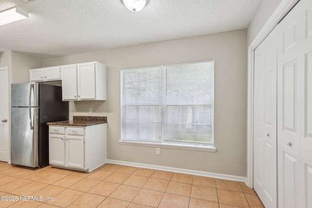 kitchen with white cabinetry, light tile patterned floors, stainless steel fridge, and a textured ceiling