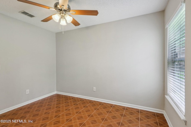 spare room with ceiling fan, a healthy amount of sunlight, and a textured ceiling