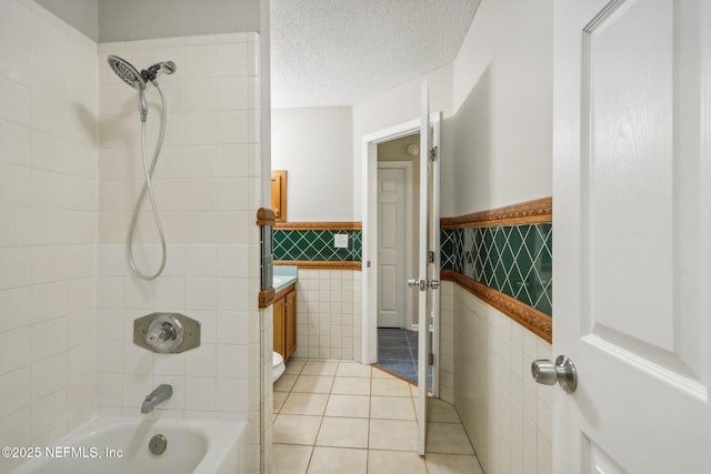 bathroom with tile patterned floors, a textured ceiling, tile walls, vanity, and tiled shower / bath combo