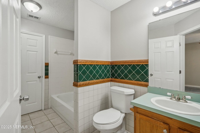 bathroom featuring tile patterned flooring, vanity, toilet, and a textured ceiling