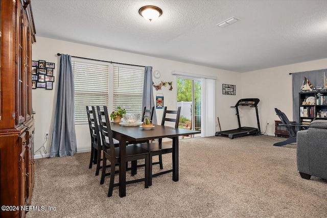 dining area with light colored carpet and a textured ceiling