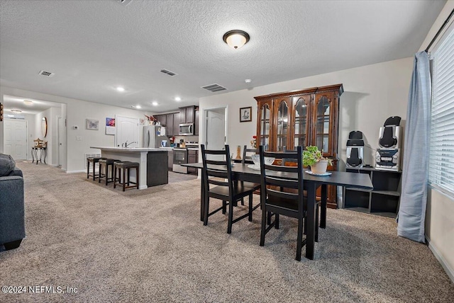 dining space with light colored carpet and a textured ceiling