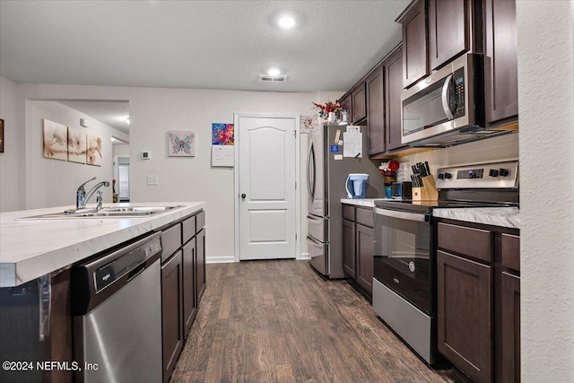 kitchen featuring sink, dark brown cabinets, a textured ceiling, dark hardwood / wood-style floors, and stainless steel appliances