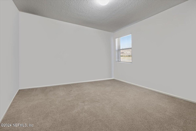 carpeted empty room featuring a textured ceiling