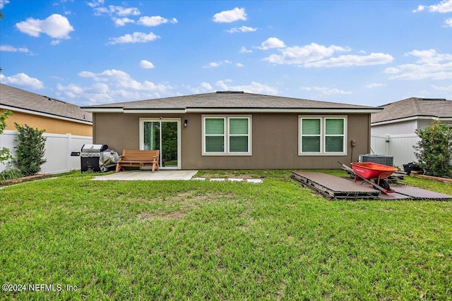 rear view of house with a wooden deck, a patio area, and a lawn