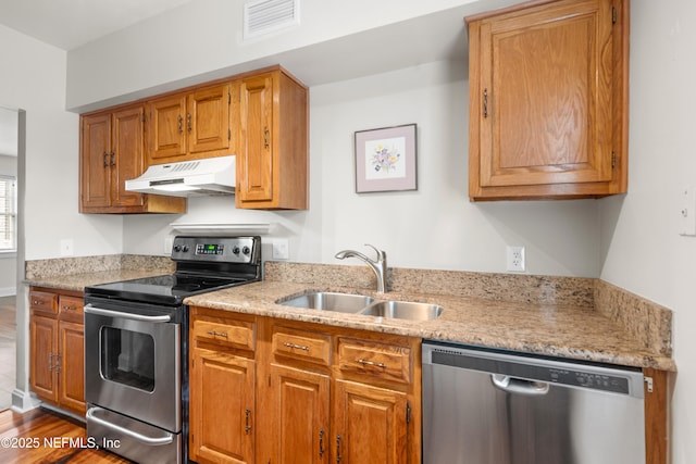 kitchen with appliances with stainless steel finishes, sink, and hardwood / wood-style floors