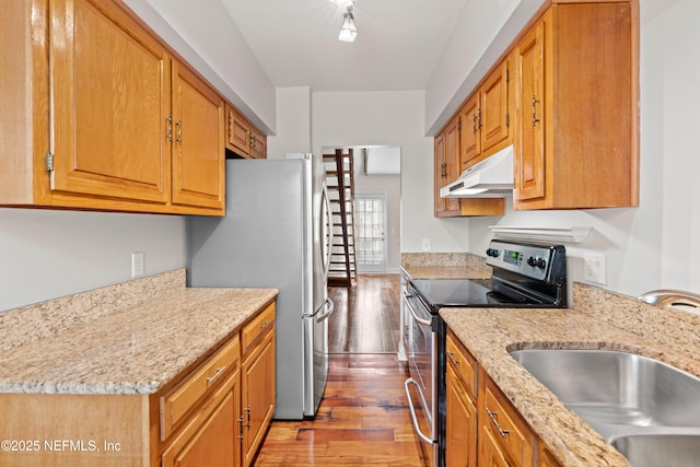 kitchen with stainless steel appliances, sink, light stone counters, and light hardwood / wood-style flooring