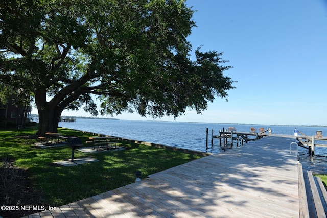 view of dock with a water view and a lawn