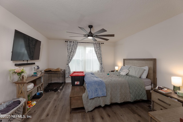 bedroom with dark wood-type flooring, ceiling fan, and a textured ceiling