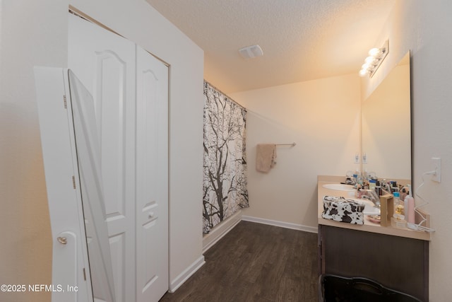 bathroom with wood-type flooring, vanity, and a textured ceiling