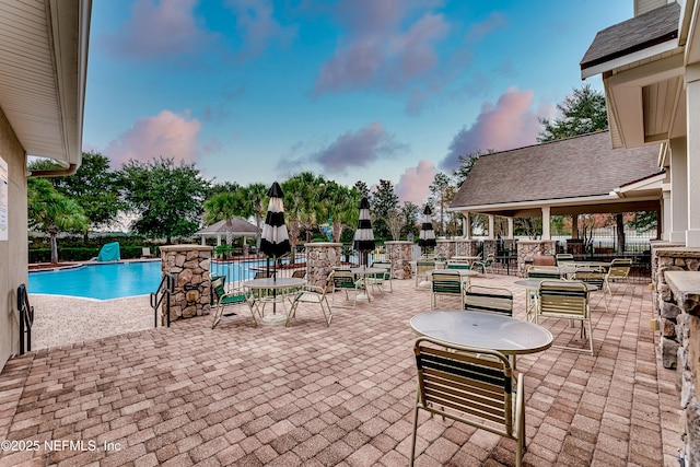 patio terrace at dusk with fence and a community pool