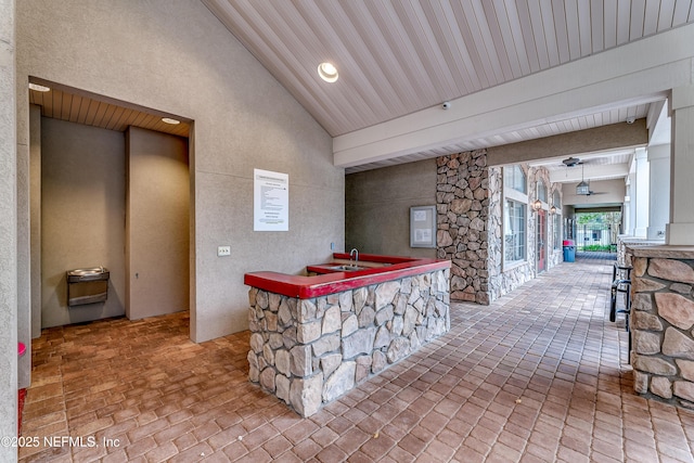 bar with a community bar, brick floor, ceiling fan, and a fireplace