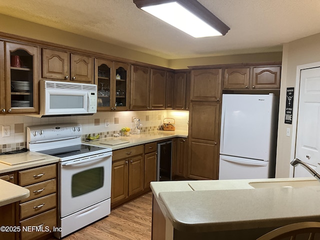 kitchen featuring sink, wine cooler, decorative backsplash, white appliances, and light wood-type flooring