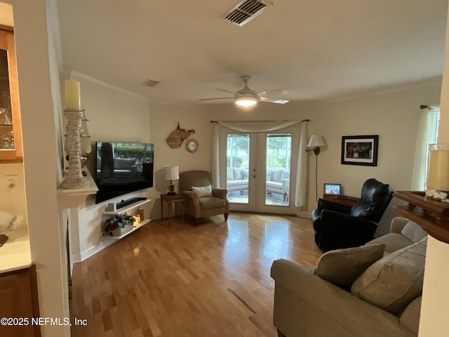 living room with ornamental molding, ceiling fan, light wood-type flooring, and french doors