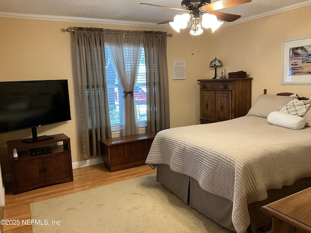 bedroom featuring a textured ceiling, ornamental molding, ceiling fan, and light wood-type flooring