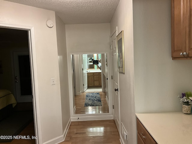 hallway with light hardwood / wood-style floors and a textured ceiling