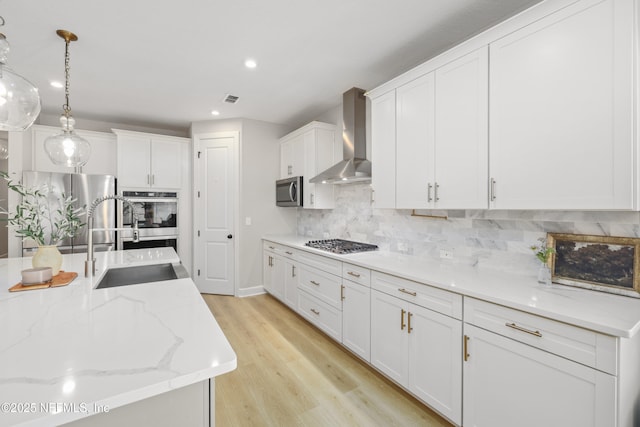 kitchen featuring stainless steel appliances, visible vents, white cabinets, wall chimney range hood, and tasteful backsplash