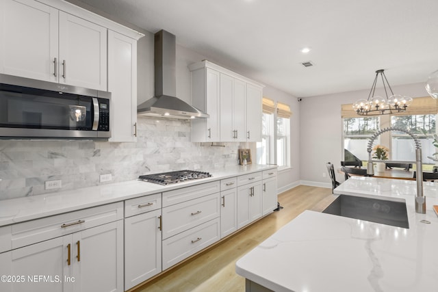 kitchen with stainless steel appliances, visible vents, white cabinets, backsplash, and wall chimney exhaust hood