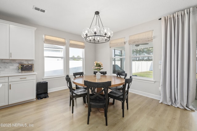 dining room with light wood-style floors, a chandelier, visible vents, and baseboards