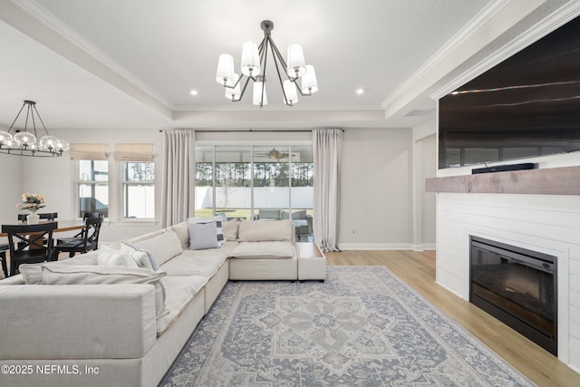 living area featuring a tray ceiling, a notable chandelier, and a glass covered fireplace