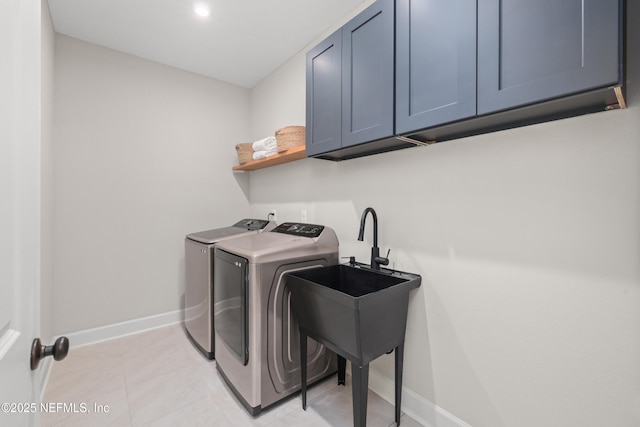 clothes washing area featuring light tile patterned floors, separate washer and dryer, a sink, baseboards, and cabinet space