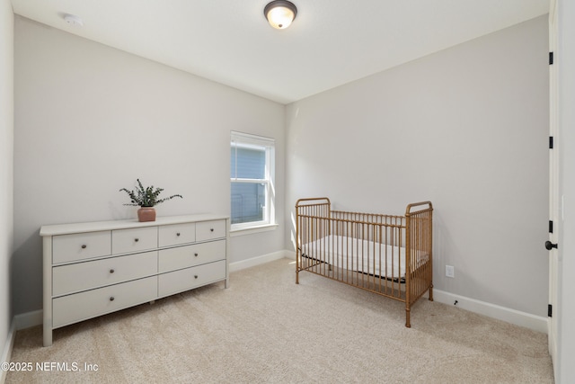 bedroom featuring light colored carpet, a crib, and baseboards