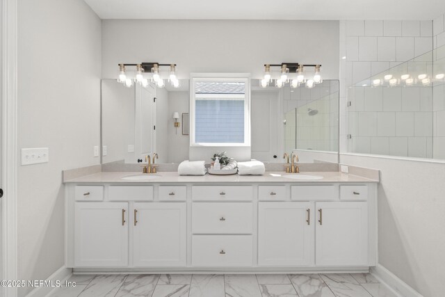 bathroom with double vanity, marble finish floor, walk in shower, and a sink