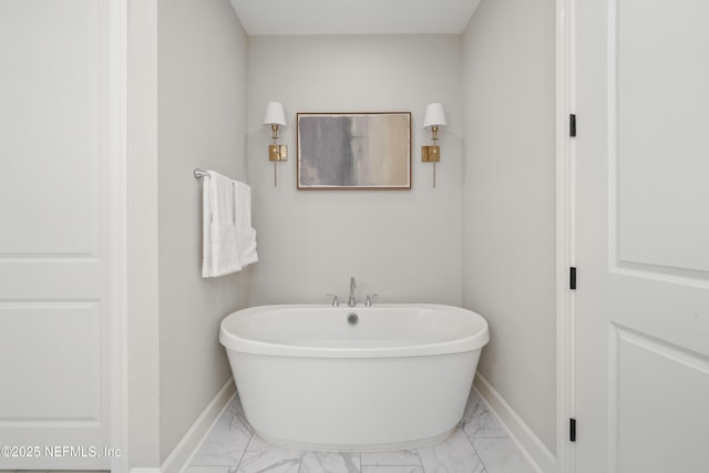 bathroom with marble finish floor, baseboards, and a soaking tub