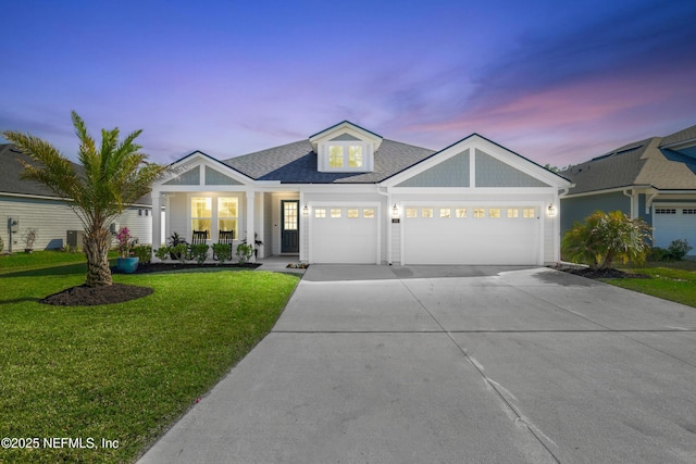 view of front of home with roof with shingles, a porch, concrete driveway, a lawn, and an attached garage