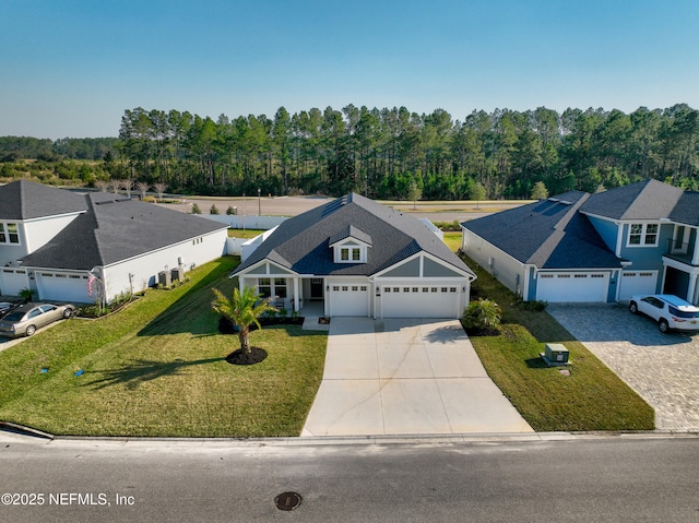 view of front of property with a garage, driveway, a view of trees, and a front yard