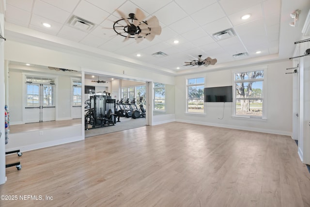 exercise room featuring light wood-type flooring, visible vents, and ceiling fan