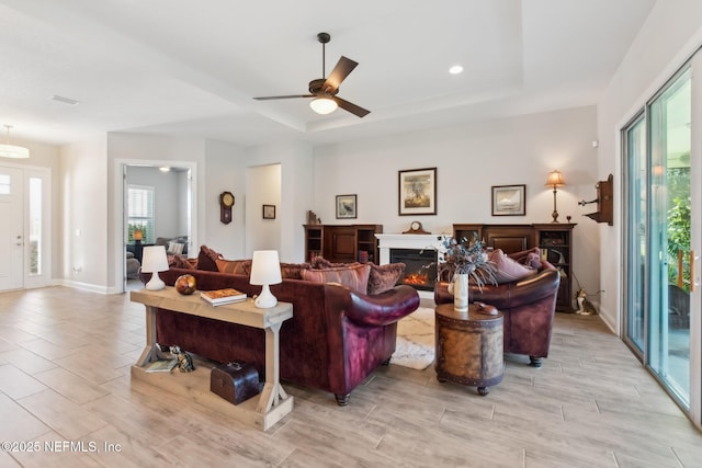 living room featuring ceiling fan and a raised ceiling