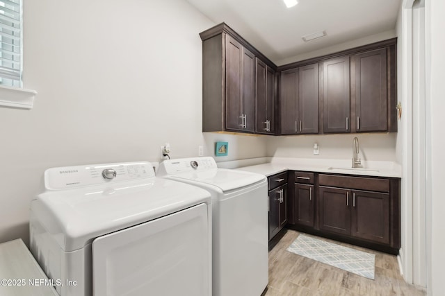 laundry area with cabinets, sink, washing machine and dryer, and light wood-type flooring